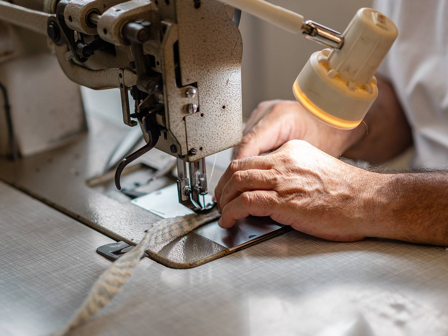 Hände führen Stoff an der Industrienähmaschine