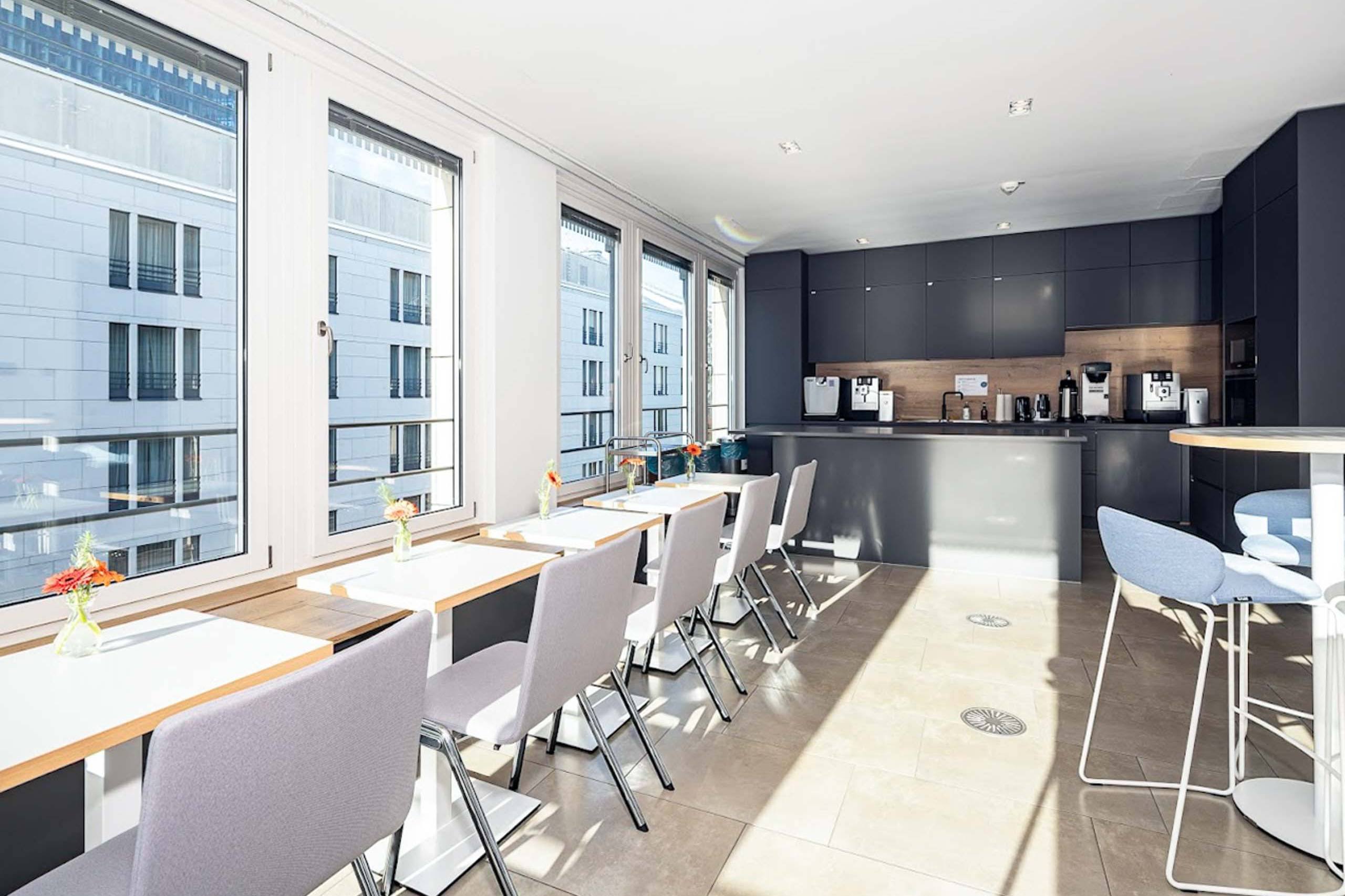 Kommunikationsbereich mit Fensterfront, Stehtischen und Barhockern
