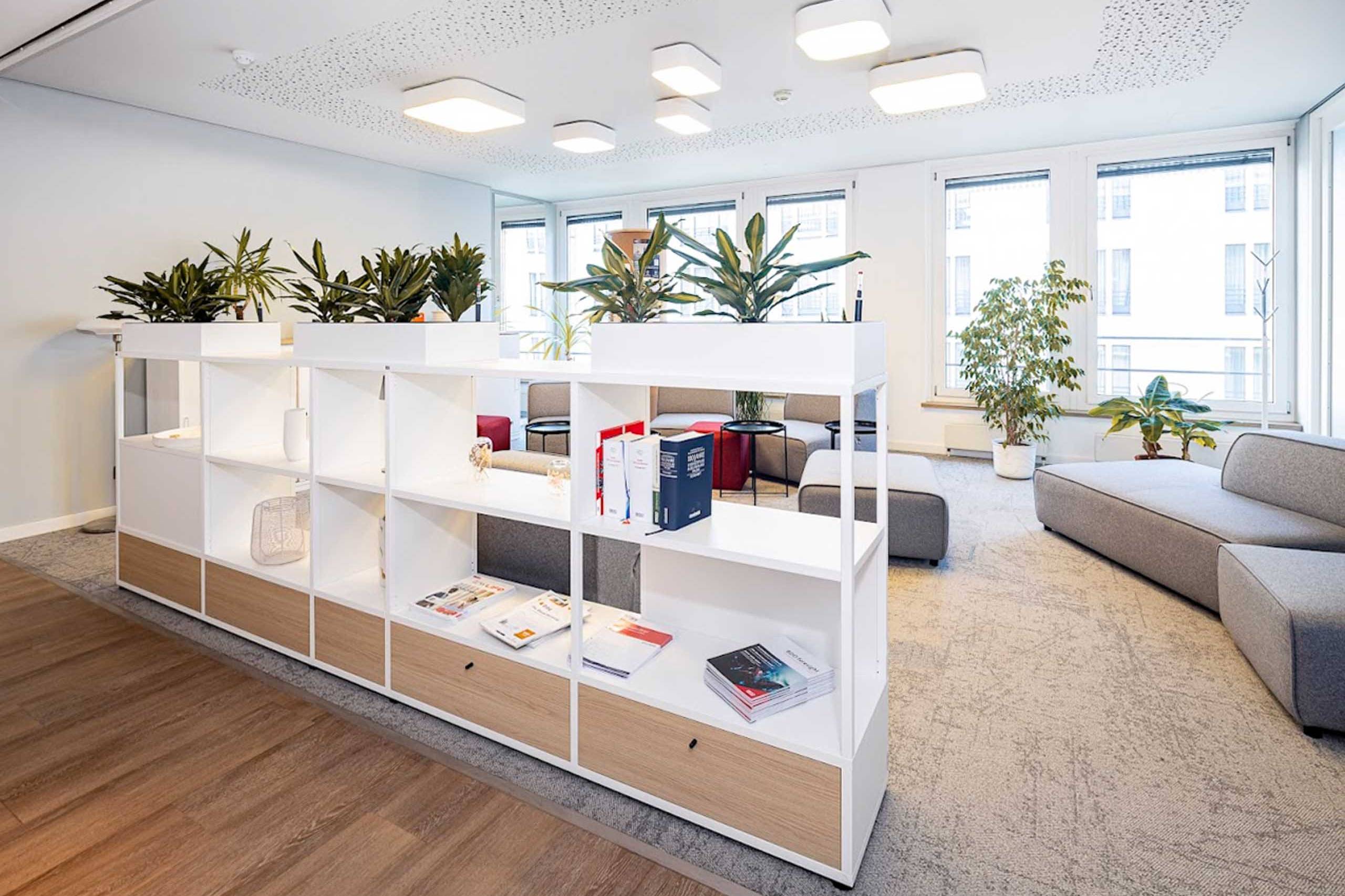 Empfangsbereich mit weißem Sideboard-Regal, Pflanzen und Loungesofa