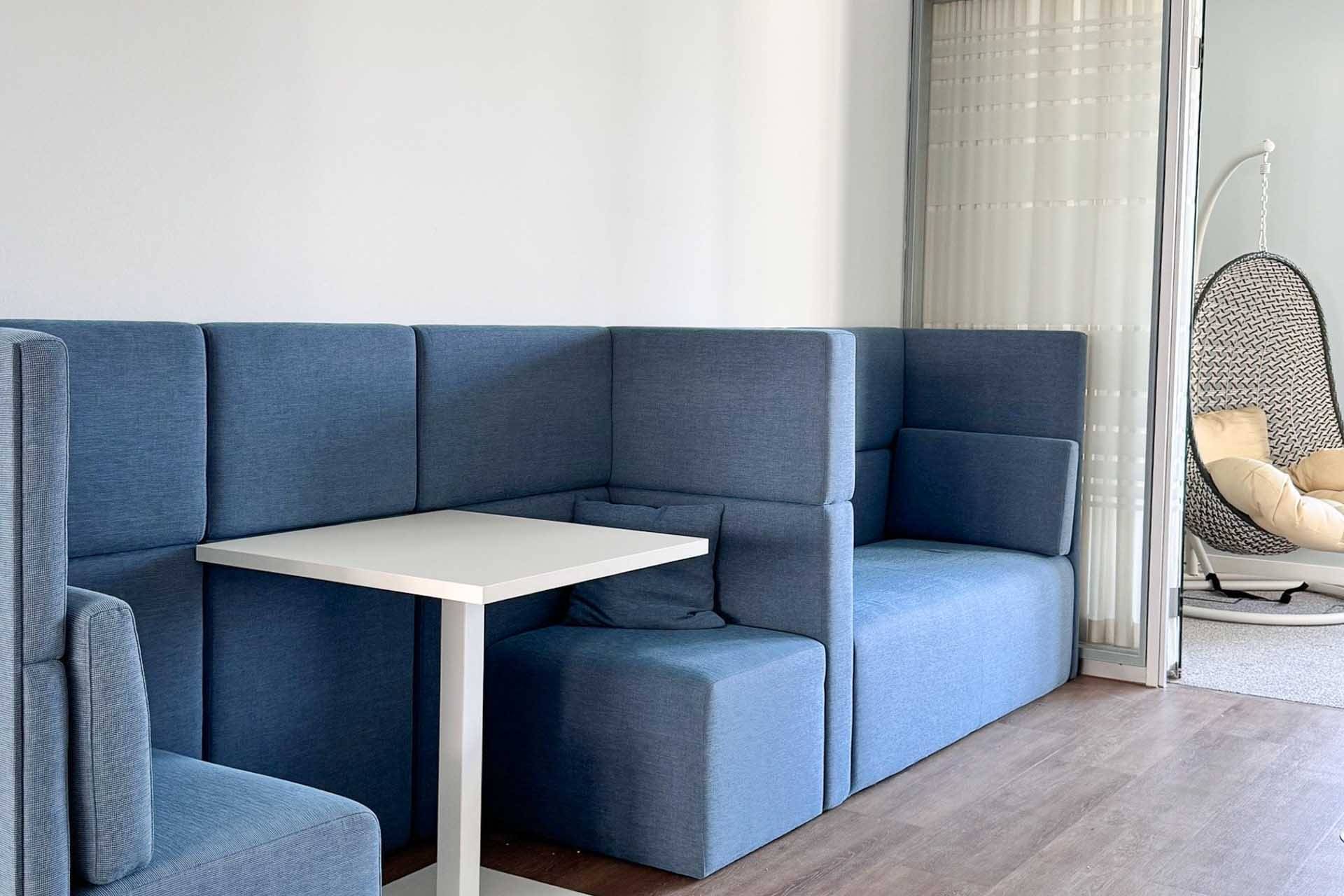 Rückzugsnische mit blauen Polsterbänken und Tisch für konzentriertes Arbeiten